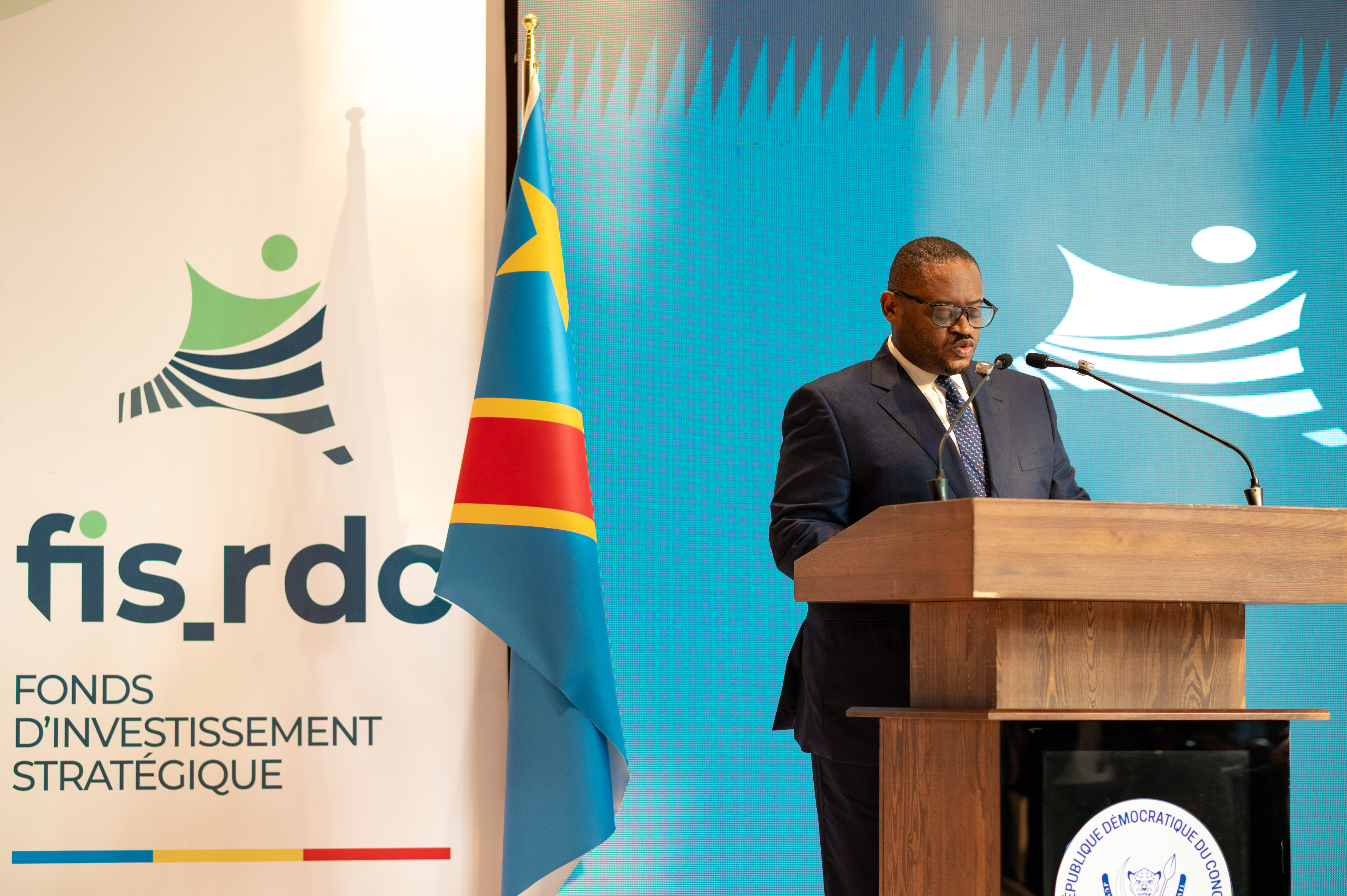 Émile OSUMBA au pupitre, aux côtés du drapeau de la RDC et du logo du FIS-RDC.